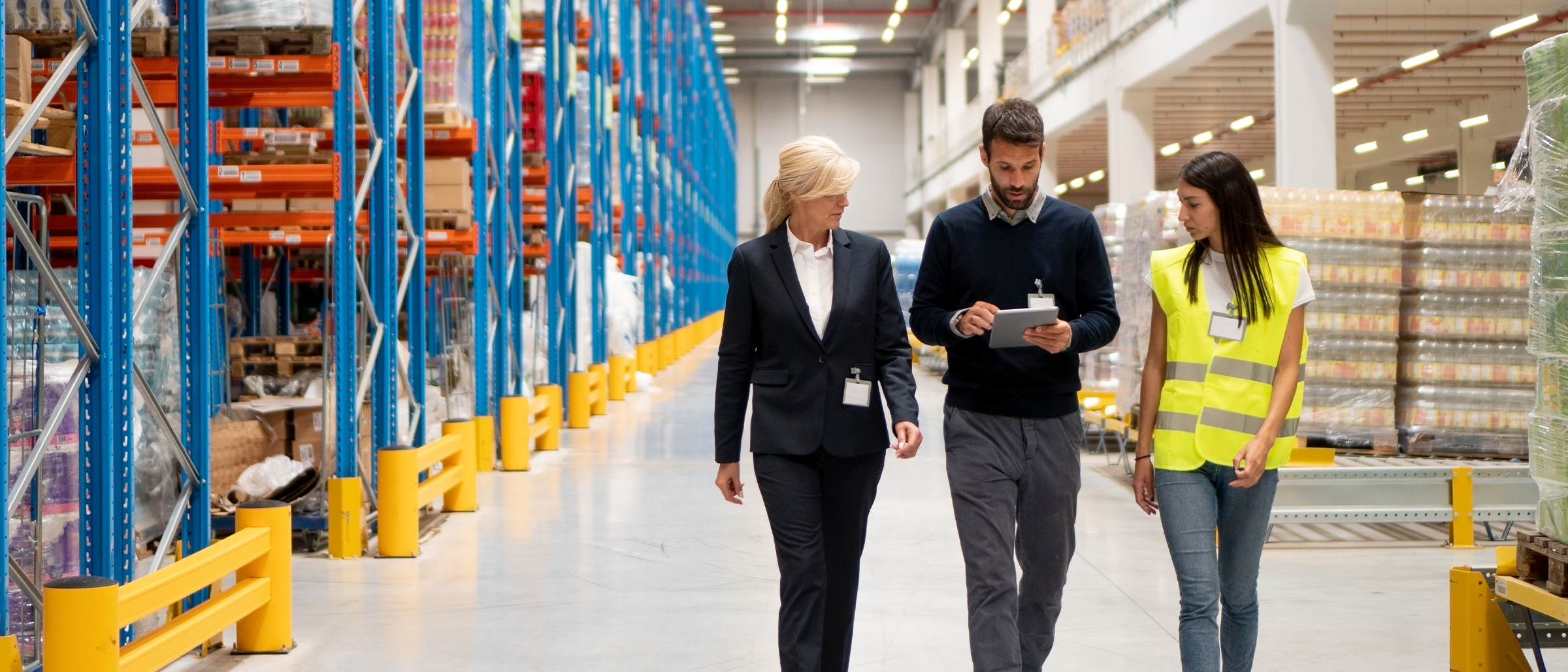 Three people walking through a manufacturing warehouse