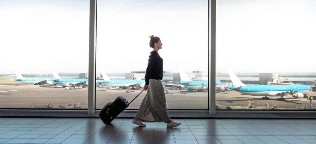 Travel nurse walking through airport with suitcase