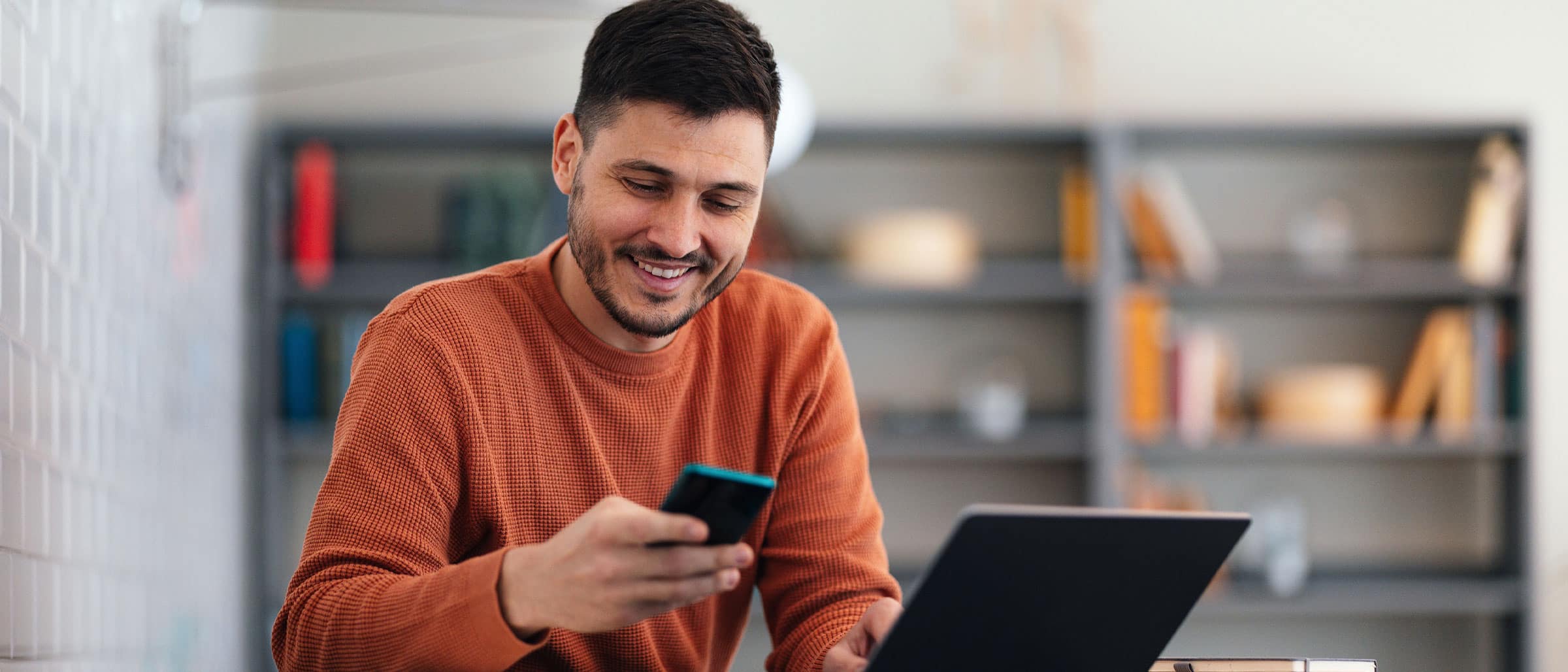 IT Recruiter smiling at phone while working on laptop