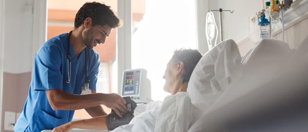 Registered nurse helping patient that is laying in hospital bed