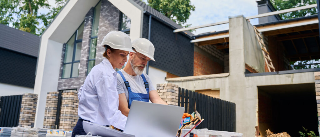 Two luxury home builder construction workers looking at blueprints