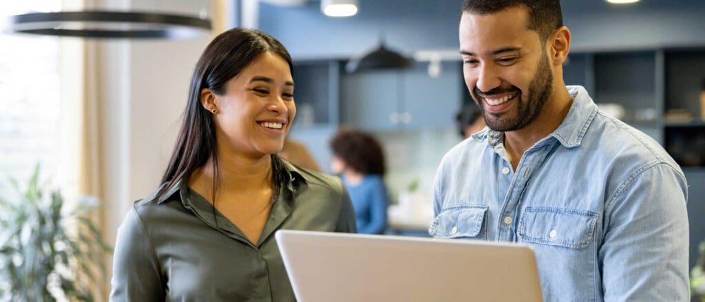 Two learning and development professionals discussing talent acquisition, looking at laptop