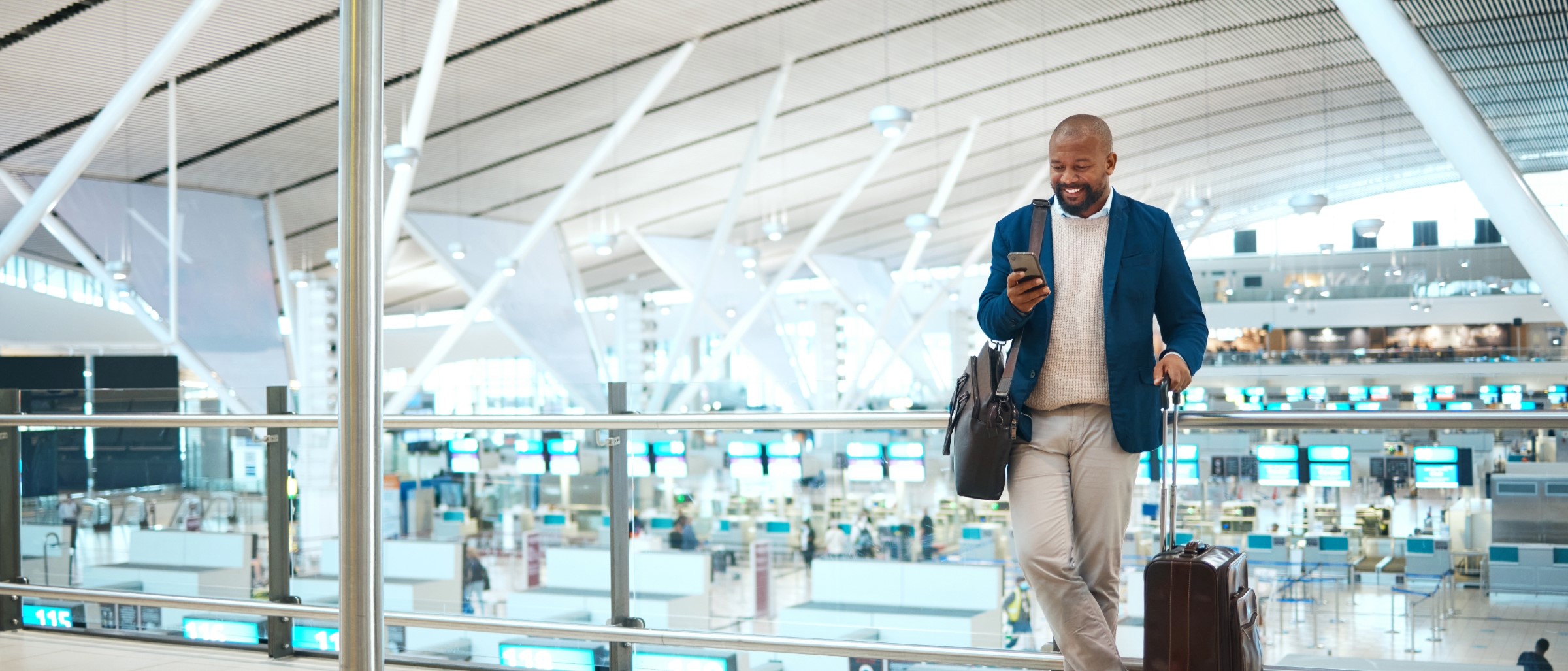 Man standing in airport smiling at phone