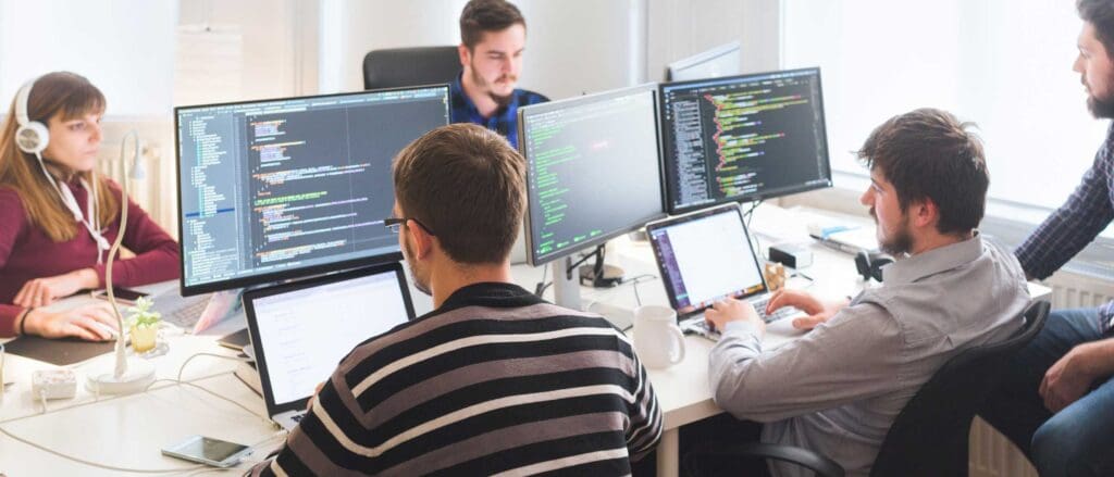 Room full of software developers each working on a computer, coding