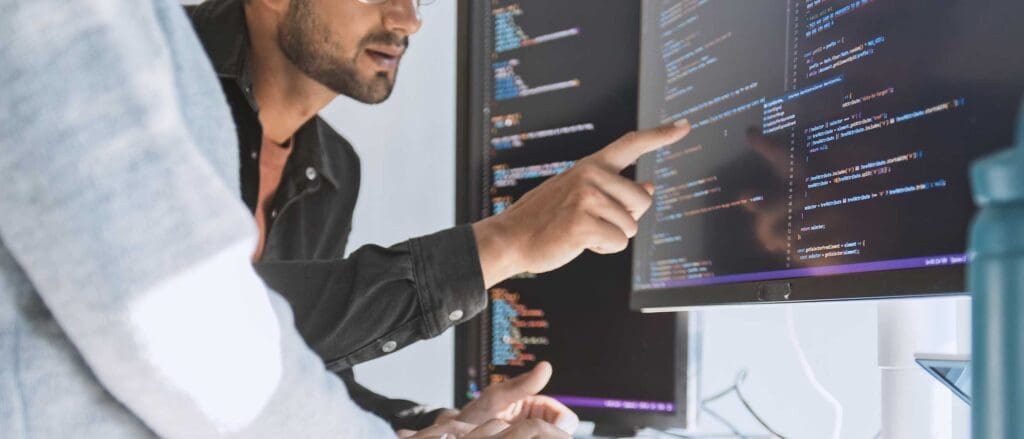 Close up of a man pointing at a line of code on a computer