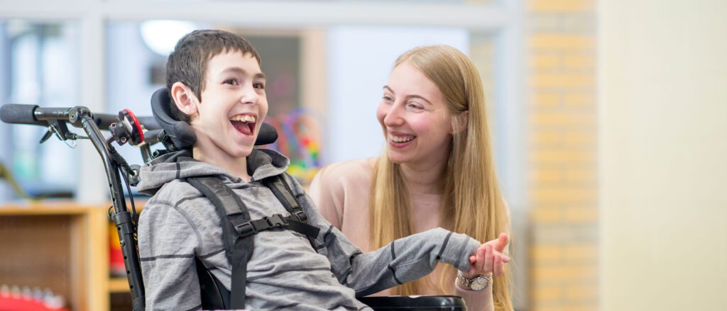 Child in wheelchair being assisted by educational service professional