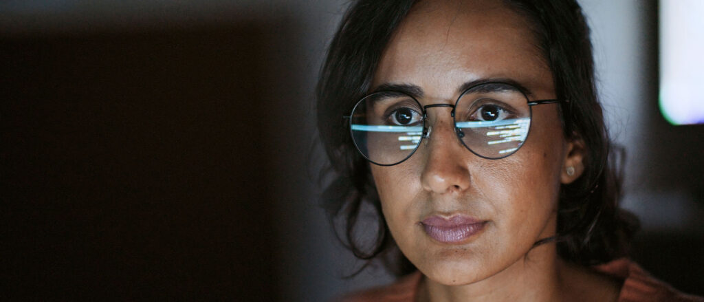 Woman wearing glasses, with code in glasses reflection