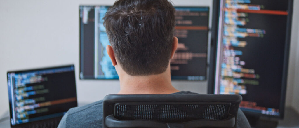 Overhead shot of a man programming on three monitors