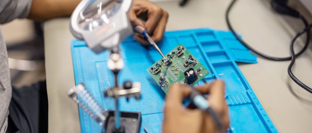 Close up of someone using soldering tools on a microchip