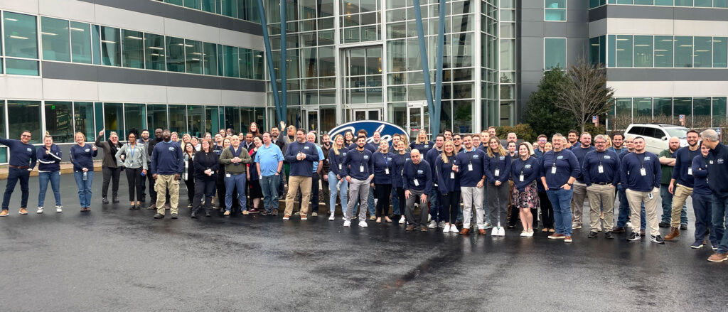 Large group of Judge employees in front of HQ sign