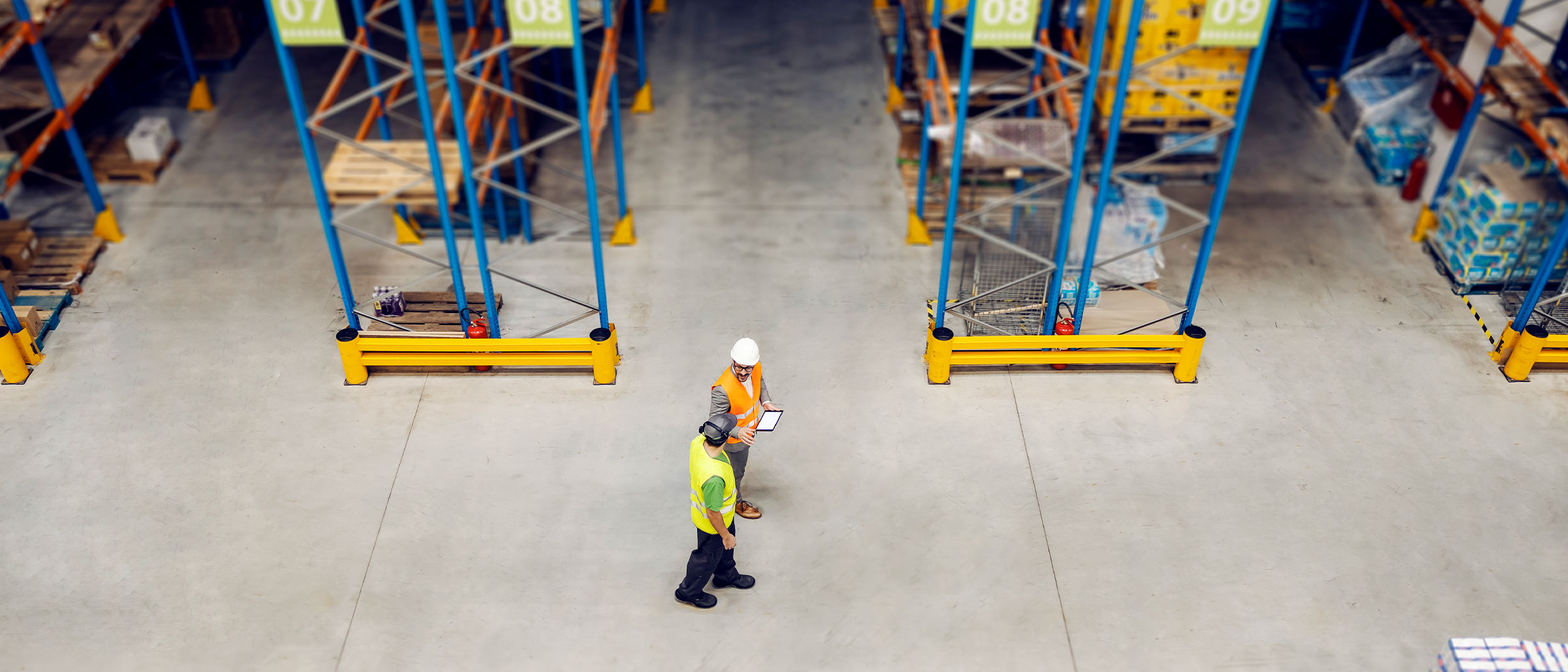 Two men wearing hardhats walking through manufacturing factory