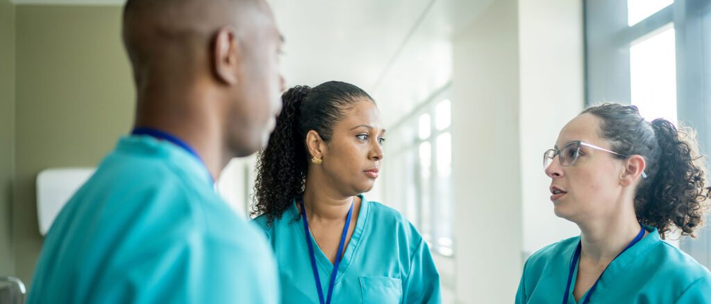 Three nurses standing around a room talking