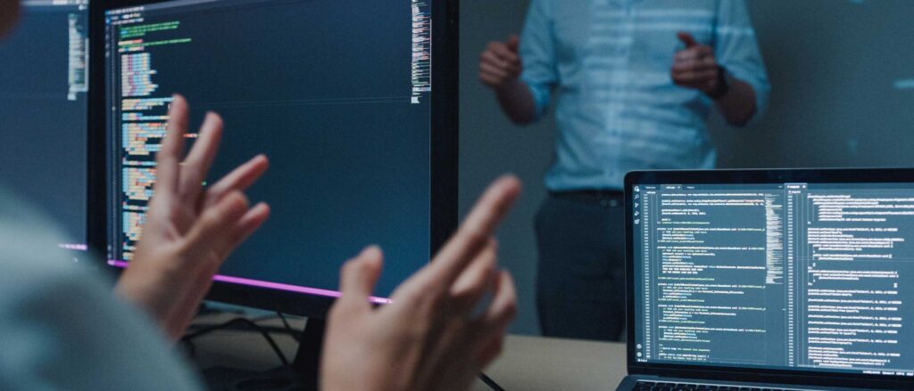 Person pointing a computer with code on it