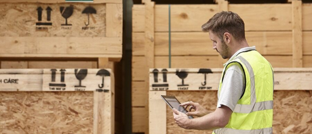 Man in warehouse wearing reflective vest on tablet